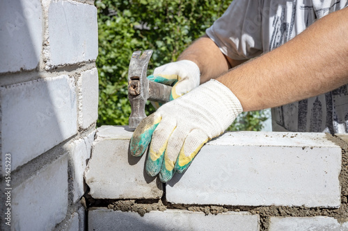 men's hands fix the brickwork with a hammer