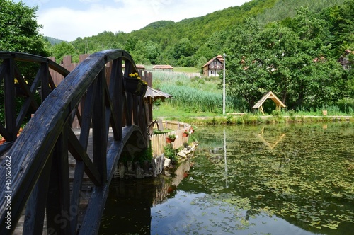 Fototapeta Naklejka Na Ścianę i Meble -  a wooden bridge, a wooden summer house and their reflection in the lake