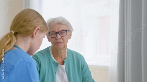 Wallpaper Mural Senior lady with glasses talks to young caretaker by window Torontodigital.ca