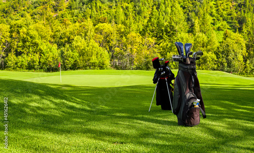 Golf bag and clubs at the edge of the green of a golf course on a sunny summer day photo