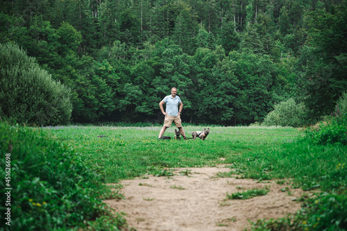 Man standing in a field with two french bulldogs