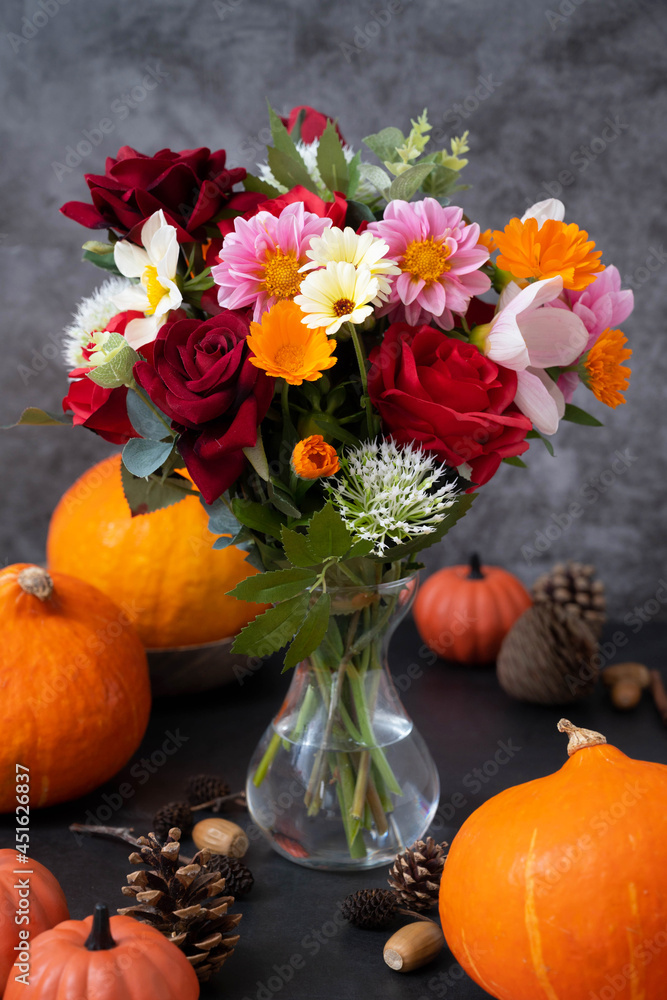 Autumn pumpkins and flowers on dark background, fall warm and cozy composition Autumn pumpkins and flowers on dark background, fall warm and cozy composition