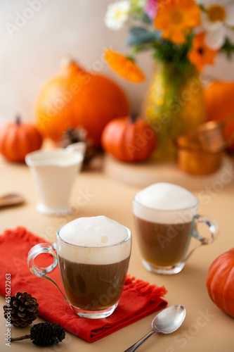 Two glass cups of pumpkin autumn latte warm drink with whipped cream. Autumn cozy beverage.