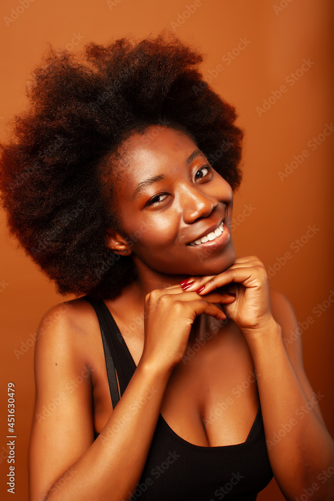 pretty young african american woman with curly hair posing cheerful gesturing on brown background, lifestyle people concept pretty young african american woman with curly hair posing cheerful gesturing on brown background, lifestyle people concept