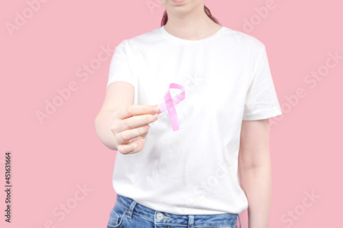World Breast cancer day concept. Woman in white T-shirt holds pink ribbon in hand. October Breast Cancer Awareness month