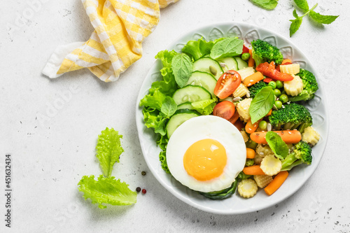 Healthy steamed and raw  vegetables fried egg bowl. Top view, space for text.