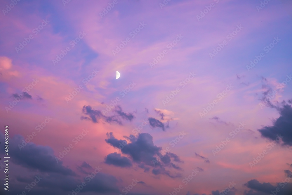 Majestic dusk. Twilight in the evening with gentle sunlight. Abstract nature background. Pink, purple, lilac colors of sky with dark clouds and young moon in sunset 