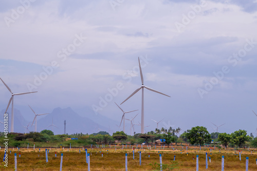 Windmill - Wind turbine below the mountain on the agriculture land. Alternate energy source generator with environment friendly. Wind turbines for ecological power supply 