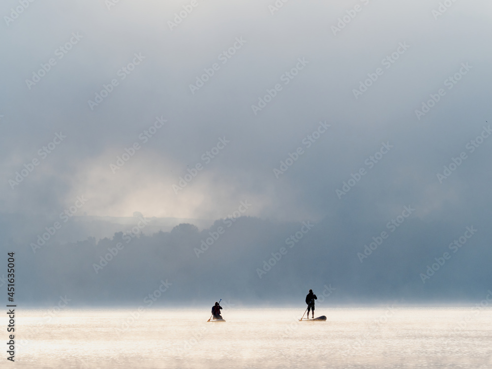rowers crossing the lake in the morning mist rowers crossing the lake in the morning mist