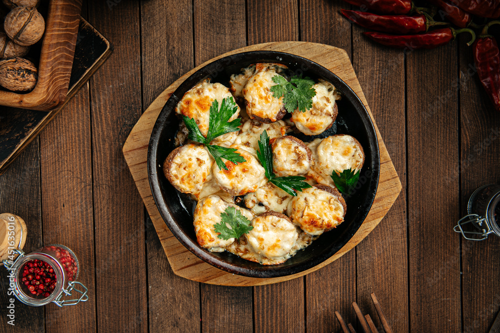 Georgian baked mushrooms with suluguni cheese on a wooden background Georgian baked mushrooms with suluguni cheese on a wooden background