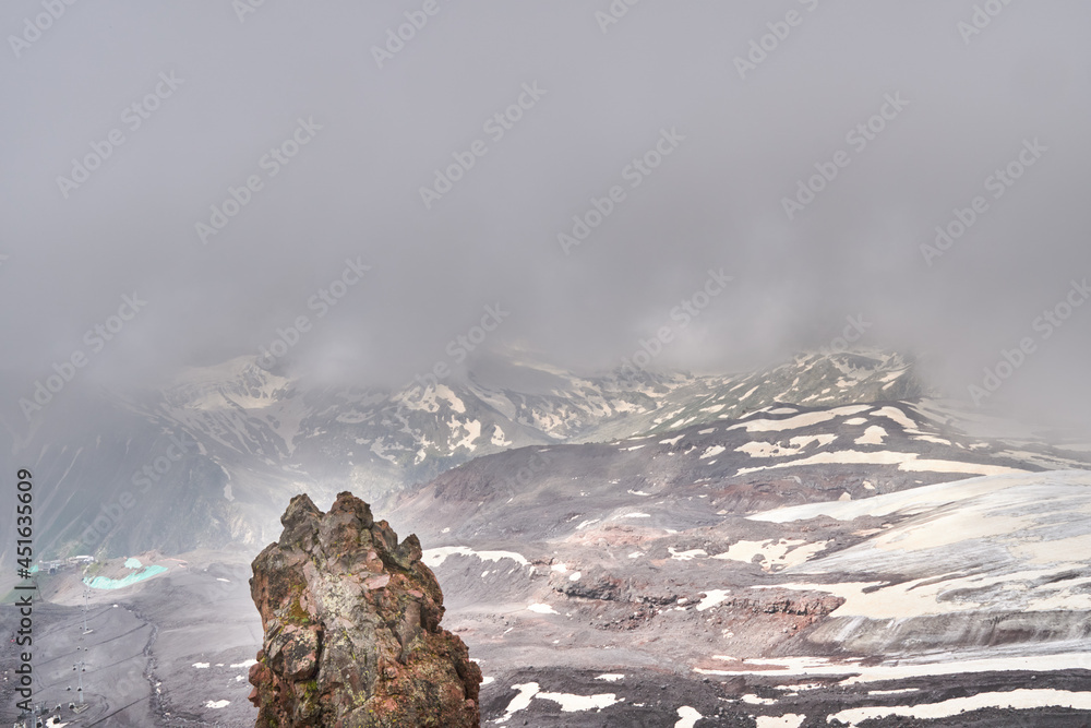 mountain slopes and black volcanic rock covered with snow. low clouds over the rutted peaks