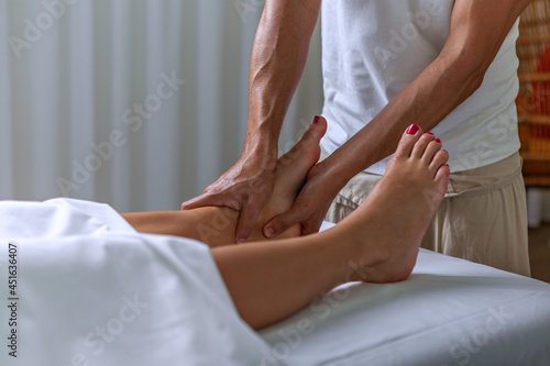 Professional therapist giving reflexology foot massage to a woman in spa center