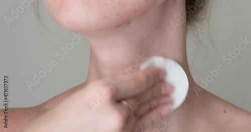 Close up woman applying skin care serum or toner on her neck. with cotton pad. Neck skin care concept photo