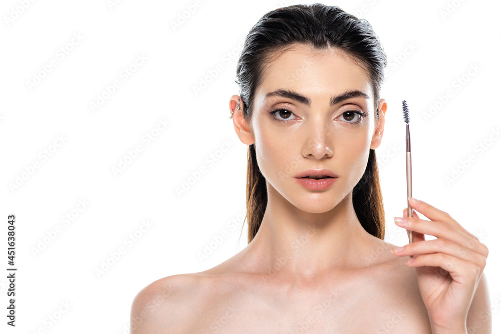 young woman with bare shoulders holding eyebrow brush isolated on white