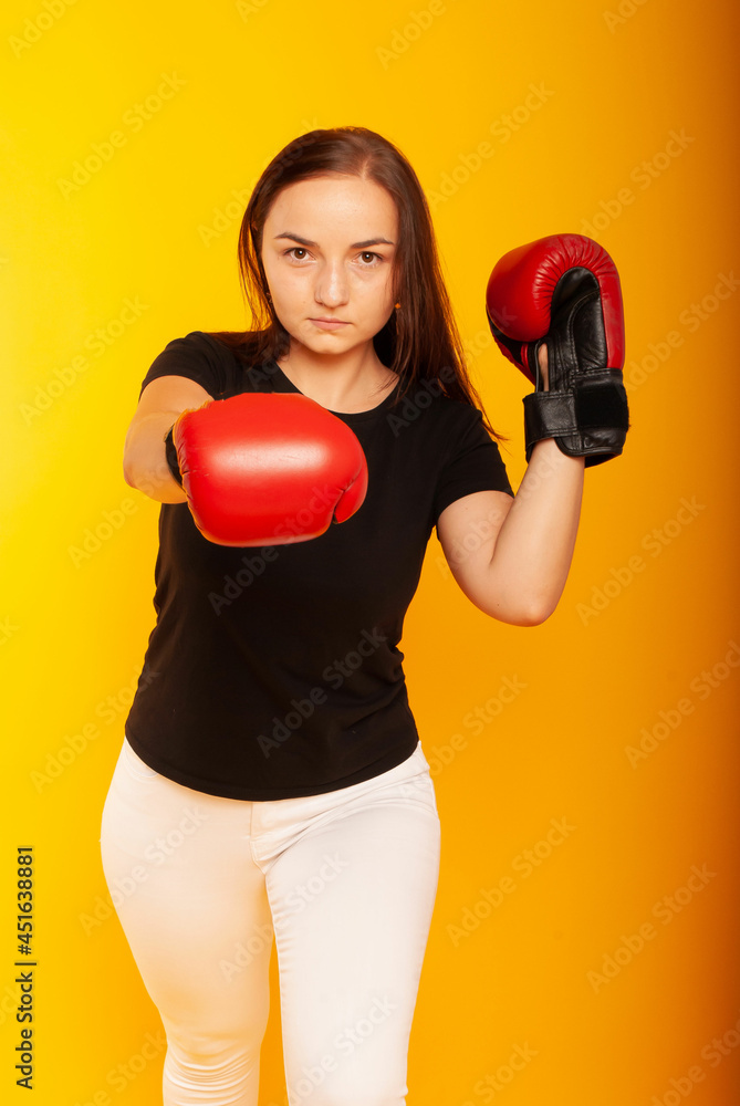 Image of a strong young woman boxer posing isolated over a yellow background wall wearing boxing gloves. Image of a strong young woman boxer posing isolated over a yellow background wall wearing boxing gloves.