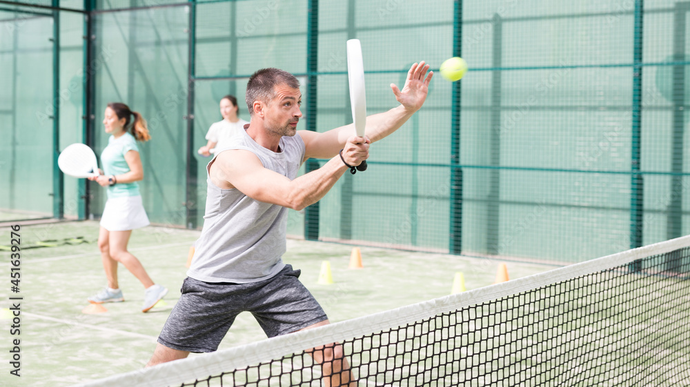 Obraz premium Man training to play tennis on the padel court outdoor. Athletes training in the background