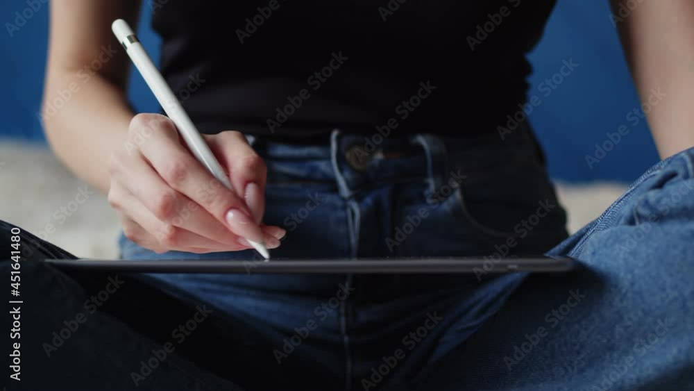 Women's hands draw on digital tablet, closeup. Woman is sitting in lotus position and drawing with stylus on tablet, closeup. Graphic design concept Women's hands draw on digital tablet, closeup. Woman is sitting in lotus position and drawing with stylus on tablet, closeup. Graphic design concept