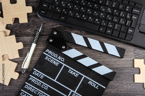 cinematic  clapper, pc keyboard, pen and puzzle pieces on a table photo