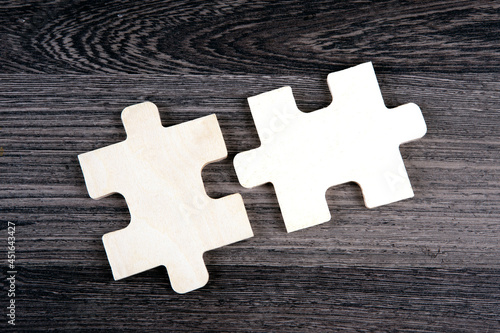 Two puzzle pieces in a row on a wooden background photo