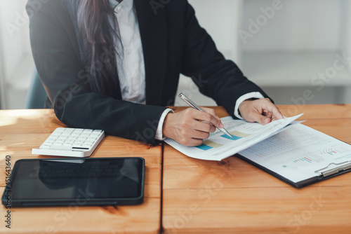 Close-up of businesswoman holding a pen pointing to graph at the office accounting work.