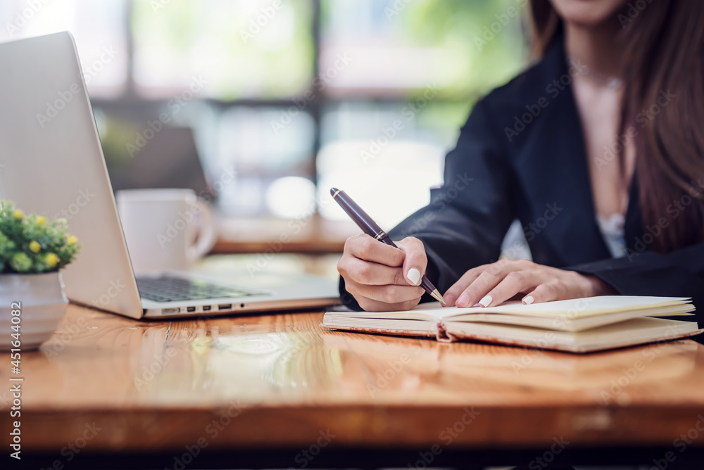Close-up of a businesswoman hand holding a pen and taking notes working at the office. Close-up of a businesswoman hand holding a pen and taking notes working at the office.