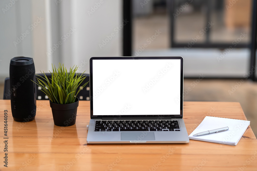 Fototapeta premium Laptop blank white screen with Bluetooth speaker notebook placed at office desk.