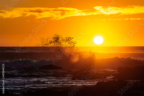 Sunset behind the waves on a beautiful beach in Portugal with rocks