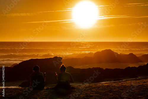 Sunset behind the waves on a beautiful beach in Portugal with rocks