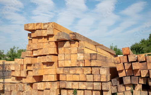 Stack of softwood lumber in a lumber shop outdoors against blue sky photo
