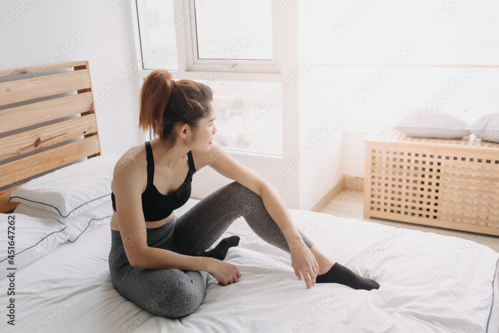 Asian woman in sport wears is resting after workout in her bedroom. Asian woman in sport wears is resting after workout in her bedroom.