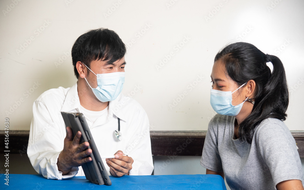 doctor meeting a patient in her office for a medical consultation, they are wearing surgical masks doctor meeting a patient in her office for a medical consultation, they are wearing surgical masks