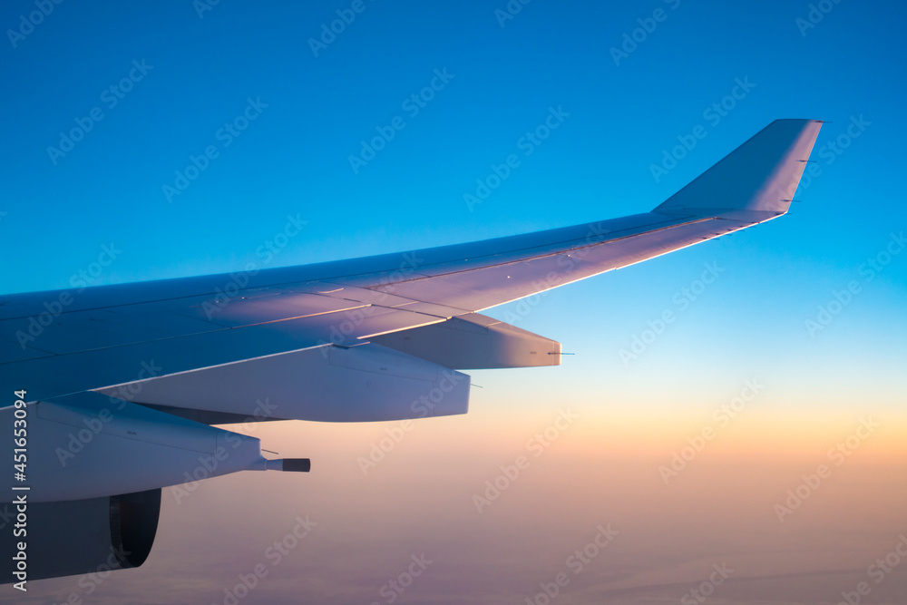 Obraz premium Airplane wing during flight at sunset
