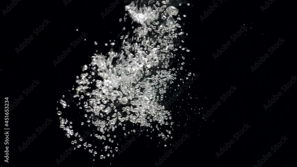 Slow motion stream of water drops down in aquarium on a black background. Slowmotion air bubbles floating under transparent water bubbles in aquarium Slow motion stream of water drops down in aquarium on a black background. Slowmotion air bubbles floating under transparent water bubbles in aquarium