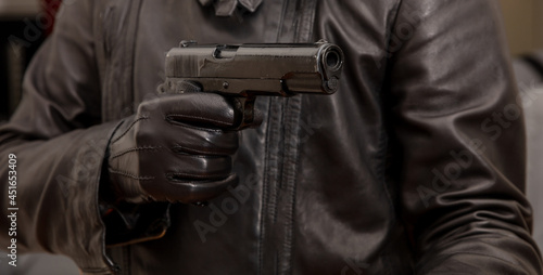 Gloved hand holding a pistol aiming, closeup view