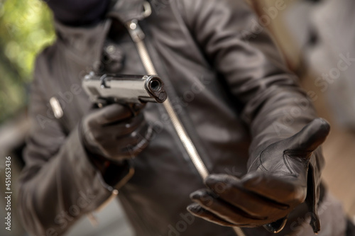 Thief gloved hand holding a pistol aiming, closeup view. Armed robbery concept photo