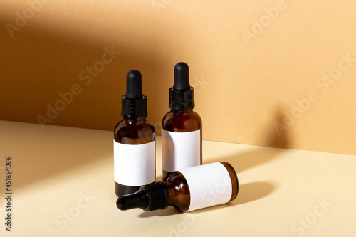 Serum and essential cosmetic oil bottle with dropper with shadows in the background. Cosmetic spa product and skin care dropper on beige background