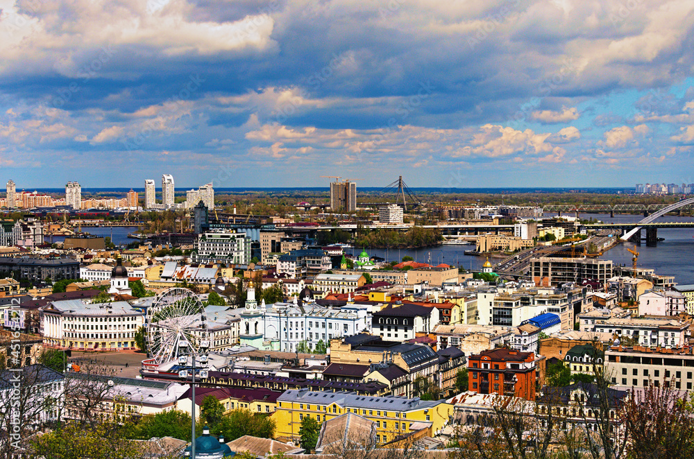 Obraz premium Scenic aerial landscape view of ancient Podil neighborhood with old colorful buildings. Skyscrapers in Obolon neighborhood on the background. Springtime in big city