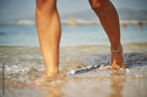 Detail of unrecognizable woman walking on beach shore