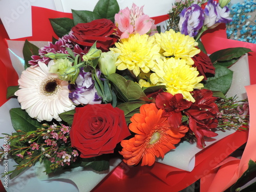 A bouquet of flowers made of yellow chrysanthemum, gerbera, Red Naomi roses. alstroemeria, eustoma and chamelacium.