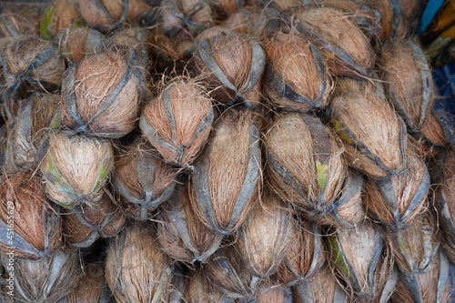 Pile of coconuts in the food market of India. Group of small whole fresh brown coconuts on retail market, close up, high angle view. Heap of many coconuts in organic farm. Coconuts in Indian market.
