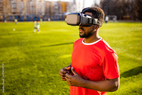 happy man in virtual reality glasses in football field background is blurred concept of virtual reality outdoors summer sunny day