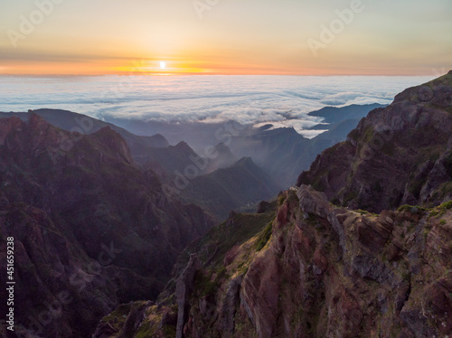 Spectacular landscape view of sunrise rising above sea of clouds surrounded with volcanic mountains.