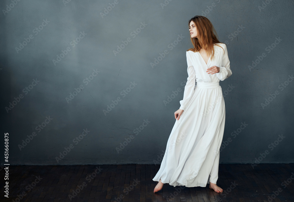 woman barefoot in a white dress dancing on a dark background woman barefoot in a white dress dancing on a dark background