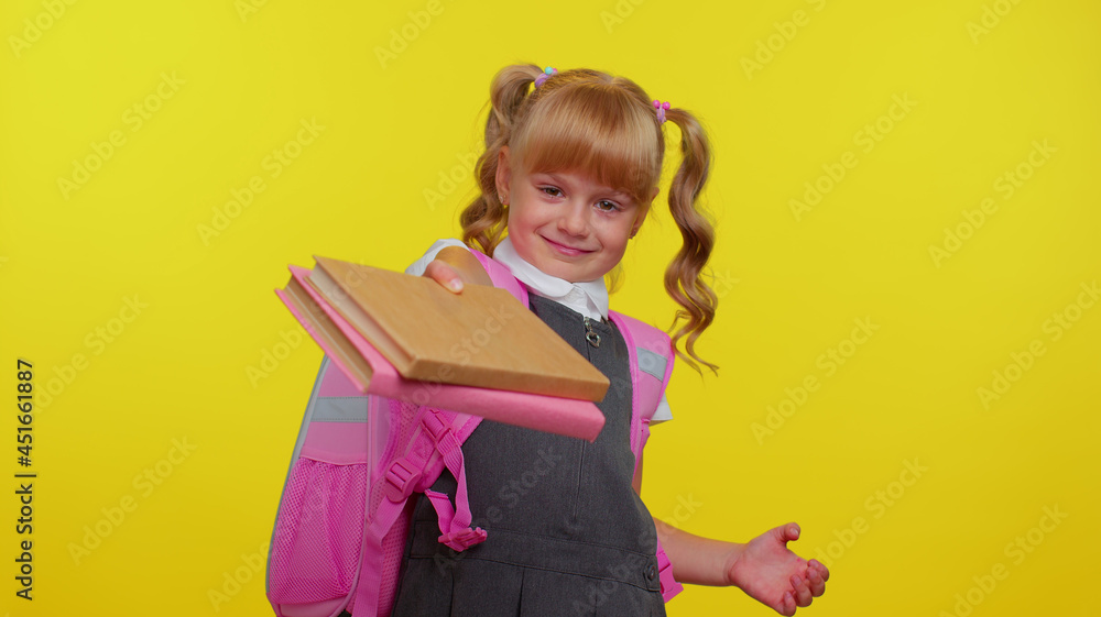 Cheerful funny blond teenage schoolgirl kid dressed in uniform showing books on camera, encourages learning together isolated on yellow studio background. Teenage education, back to school, study Cheerful funny blond teenage schoolgirl kid dressed in uniform showing books on camera, encourages learning together isolated on yellow studio background. Teenage education, back to school, study