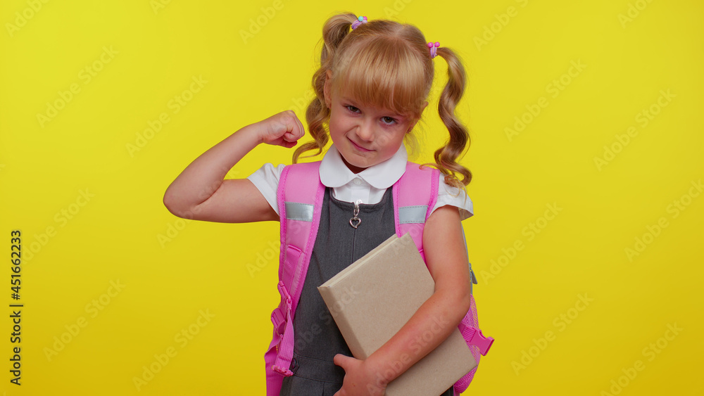 Little blonde child kid girl in school uniform showing biceps and looking confident, feeling power strength for study, energy to gain success win. Yellow studio background. Back to school. Childhood Little blonde child kid girl in school uniform showing biceps and looking confident, feeling power strength for study, energy to gain success win. Yellow studio background. Back to school. Childhood