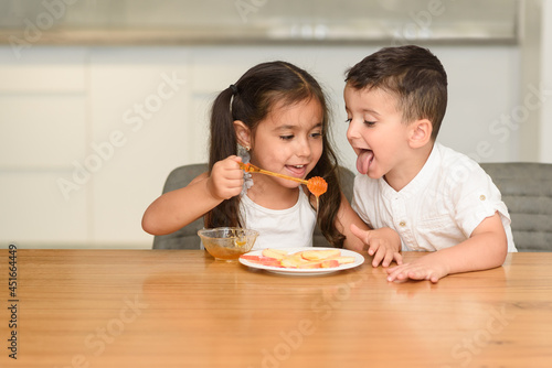 Little Funny Girl And Boy Eating Apple With Honey. Healthy Eating For Children.