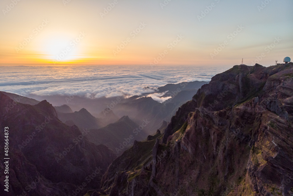 Obraz premium Spectacular landscape view of sunrise rising above sea of clouds surrounded with volcanic mountains.
