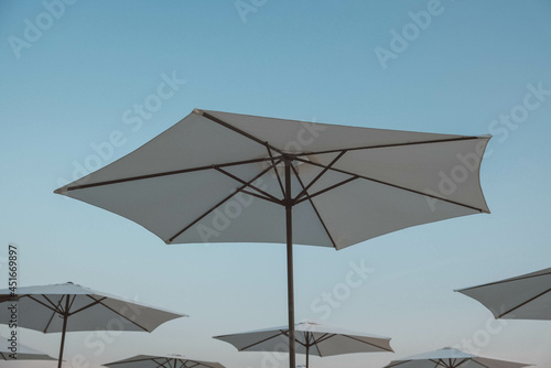 White beach umbrellas on sky background. Copy  empty space for text