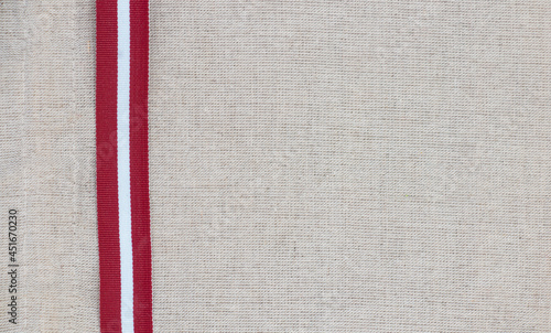 Composition of national latvian patterned ribbon flag on linen fabric photo