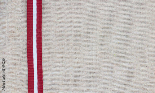Composition of national latvian patterned ribbon flag on linen fabric